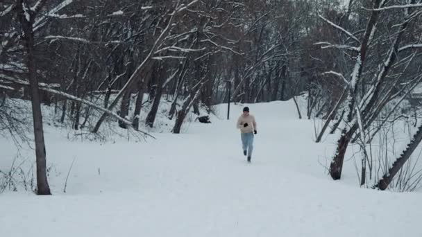 Uomo in forma che corre sulla neve nella foresta invernale — Video Stock
