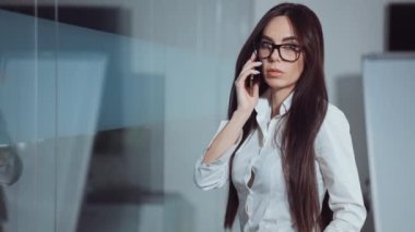 İş kadını ofiste telefonla konuşuyor.