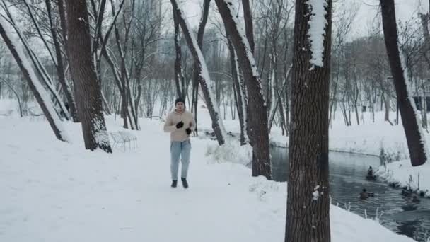 Jogger loopt op sneeuw in de buurt van rivier in park — Stockvideo