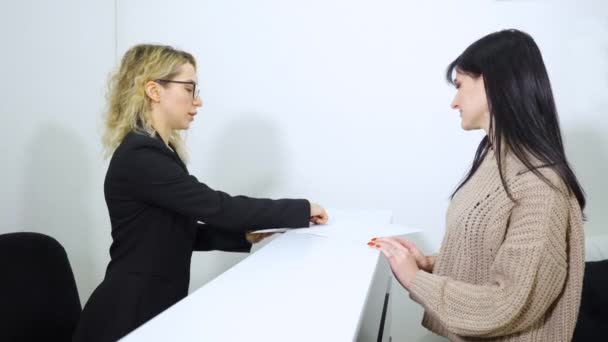 Recepción chica mostrando la lista de instrucciones a invitado — Vídeos de Stock