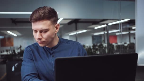 Hombre de negocios escribiendo informe sobre el ordenador portátil en la oficina de espacio abierto — Vídeos de Stock