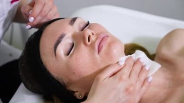 Güzellik uzmanının zaman ayarlı elleri kadın yüzünden maskeyi çıkarıyor.