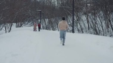 Kış parkında koşucu aileye yaklaşıyor.