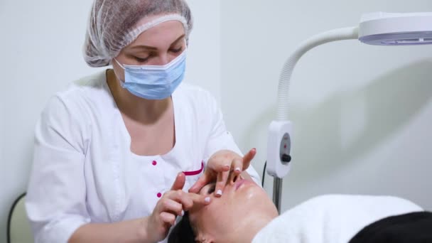 Cosmetologo che fa massaggio viso antirughe per donna in clinica di bellezza — Video Stock