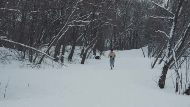 Slow motion man rent de heuvel op in het winterbos — Stockvideo