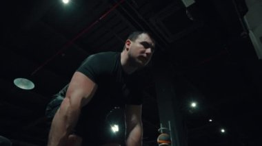 Spor salonunda halter kaldıran kaslı bir vücut geliştirici.