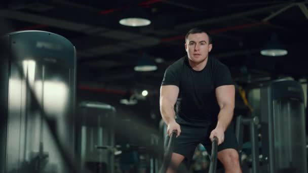 Hombre fuerte haciendo ejercicio con cuerdas de batalla en el gimnasio — Vídeo de stock