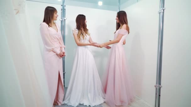 Bruid en bruidsmeisjes die jurken passen in de bruidssalon — Stockvideo