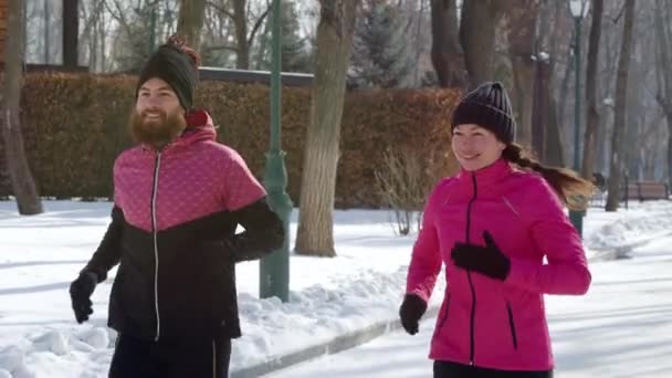 Usmívající se pár jogging v zasněženém parku — Stock video