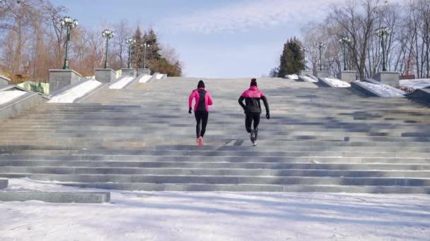 Pareja de atletas corriendo por la escalera en el parque de invierno — Vídeos de Stock