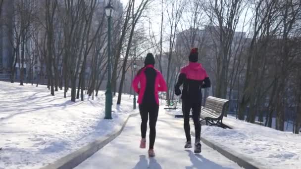 Slow motion pareja deportiva trotando en el parque de invierno — Vídeos de Stock