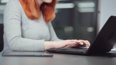 Dizüstü bilgisayar ve tablet kullanan kızıl saçlı kadının elleri.
