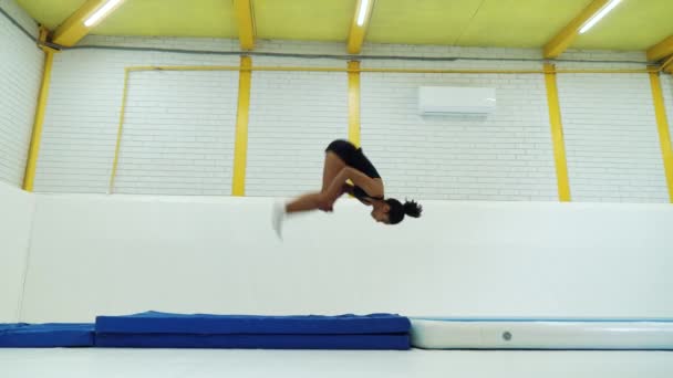 Black woman practicing back flips in gym — Stock Video