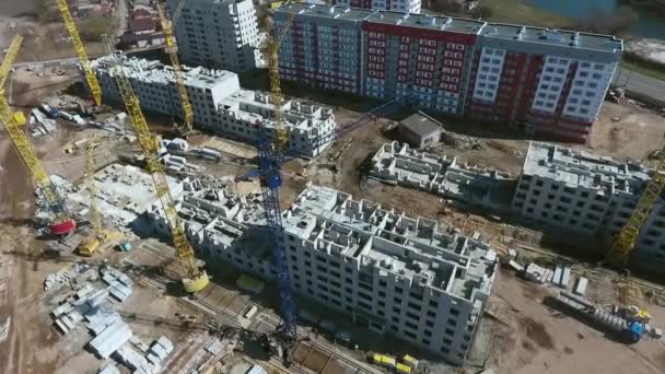 Aerial of construction site with cranes near multistory buildings — Stockvideo