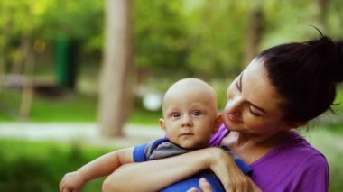 Happy mother with baby in arms posing in park