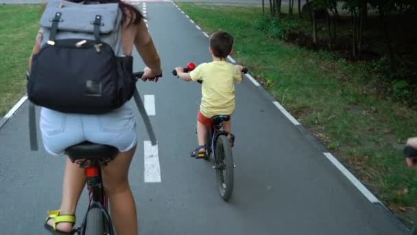 Family riding bicycles approaching red crossing on bike lane — Stok Video