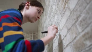 Girl writing math exercises on wallpaper