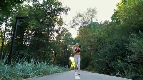 Mujer en ropa deportiva sexy trotando en el parque — Vídeos de Stock