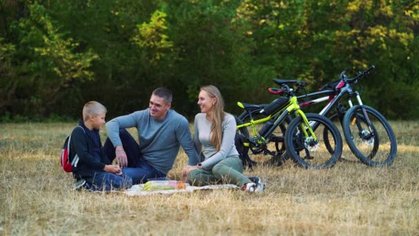 Família fazendo piquenique depois de andar de bicicleta na floresta — Vídeo de Stock