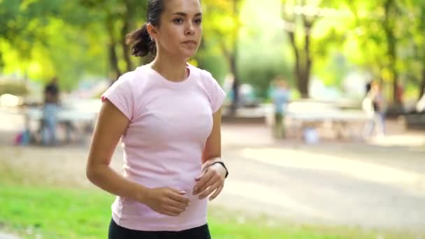 Жінка встановлює таймер на годинник, перш ніж бігти в парку — стокове відео