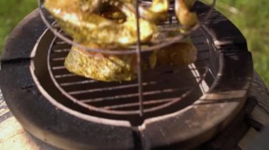 Şef seramik ızgaranın içine marine edilmiş balık koyuyor.