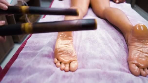 Massage mit Bambusstäben an weiblichen Füßen — Stockvideo