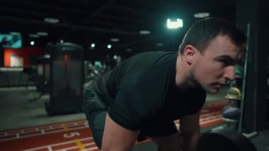 Spor salonunda halterle egzersiz yapan kaslı bir sporcu.