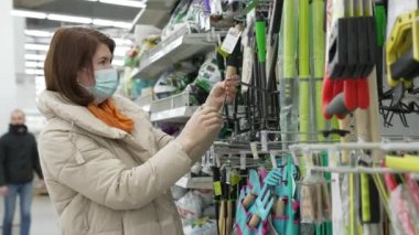 Maskeli kadın süpermarkette bahçe aletini seçiyor