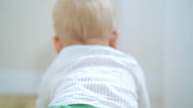 Bebek yerde sürünüyor ve oyuncaklarla oynuyor.