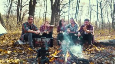 Kamp ateşinin yanında oturan gezgin blogcular video kaydediyor