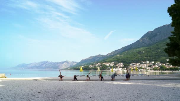 Группа людей, практикующих йогу на пляже — стоковое видео