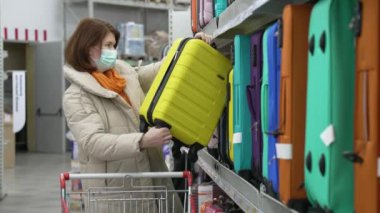 Kadın salgın sırasında süpermarketten bavul alıyor.