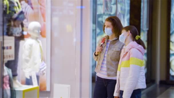 Matka i córka w maskach patrzące na witrynę sklepu — Wideo stockowe