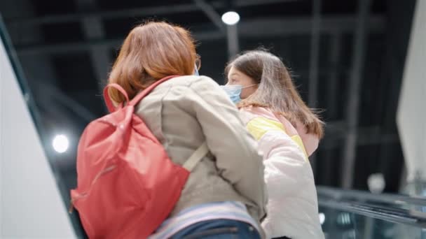 Мать и дочь поднимаются на эскалаторе в торговом центре — стоковое видео