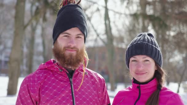 Gente en ropa deportiva sonriendo a la cámara en el parque de invierno — Vídeos de Stock