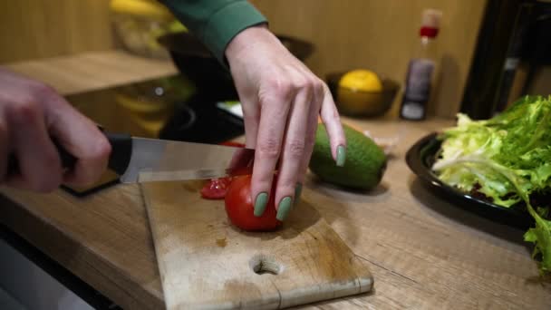 Vrouwelijke handen snijden tomaat op houten plank — Stockvideo