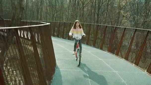 Fille à vélo sur pont arrondi — Video