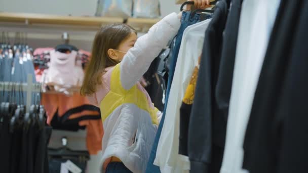 Adolescente eligiendo jeans en la tienda durante la pandemia — Vídeos de Stock