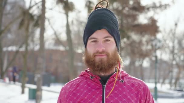 Szakállas férfi sportruházatban pózol a téli parkban — Stock videók
