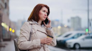 İş kadını telefonda konuşuyor ve kahve içiyor.