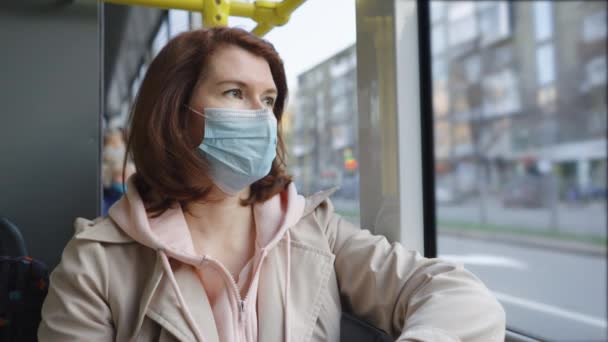 Femme masquée regardant par la fenêtre du bus — Video