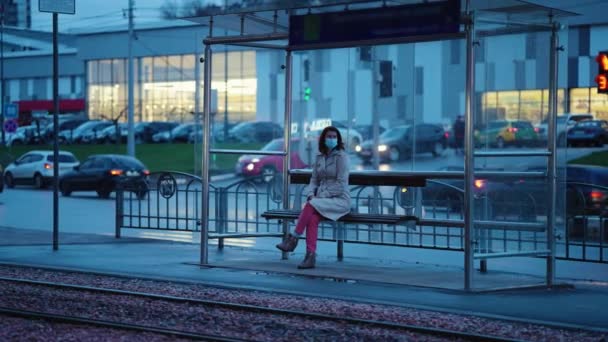 Одинокая женщина на трамвайной остановке вечером — стоковое видео