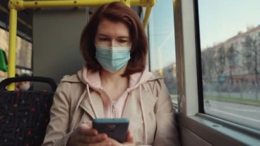 Otobüste seyahat eden ve telefon kullanan bir kadın.
