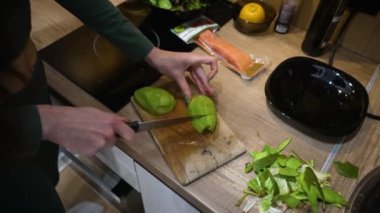 Avokadoyu parçalara ayıran kadın elleri.