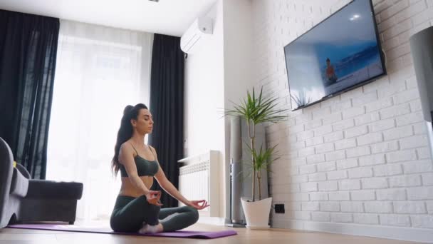 Nő ül lótusz testtartás és meditál otthon — Stock videók