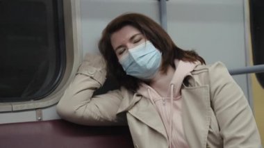 Maskeli kadın metroda uyuyor.