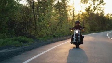 Motosikletli gün batımında kır yolunda