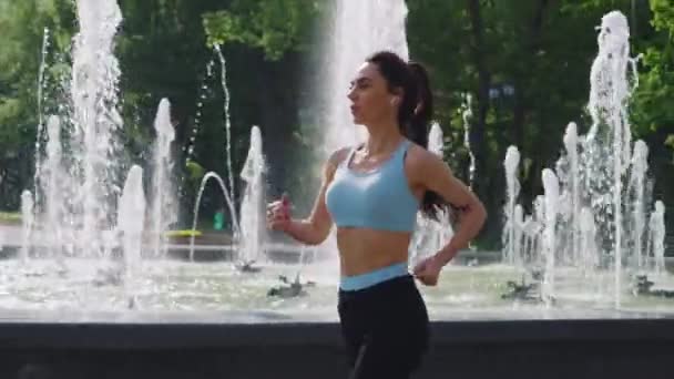 Fitte Frau joggt um Brunnen — Stockvideo