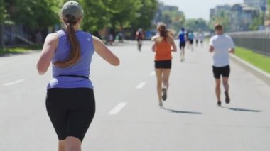 Artı boy kadın maraton koşuyor ve nabzını kontrol ediyor.