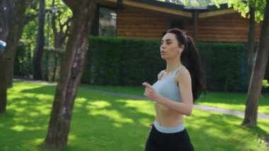 Park yerinde kulaklıkları olan yavaş çekimde koşan kadın koşucu